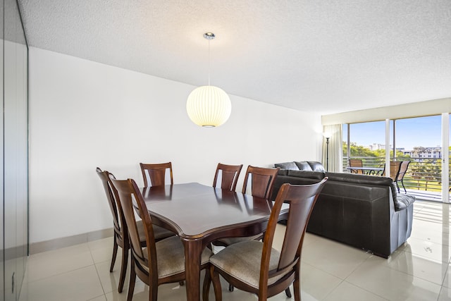 dining room with a textured ceiling, light tile patterned flooring, and baseboards