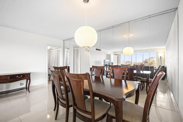 dining room featuring light tile patterned floors, a textured ceiling, visible vents, and baseboards