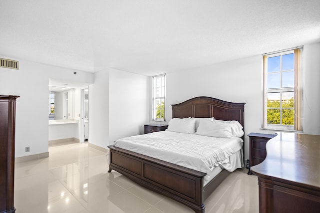 bedroom featuring light tile patterned floors, a textured ceiling, connected bathroom, visible vents, and baseboards