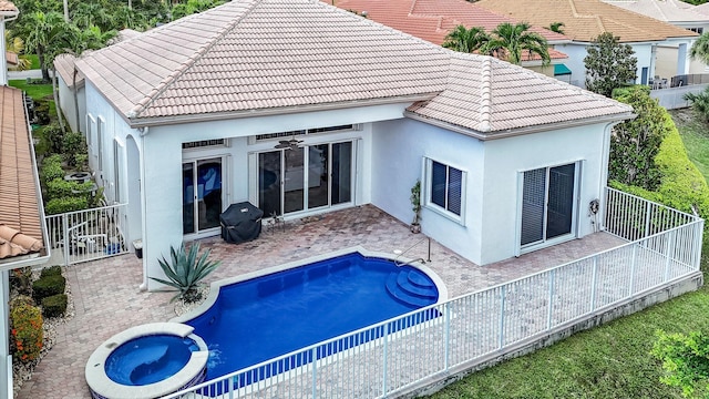 back of house with a ceiling fan, a patio, a tile roof, a pool with connected hot tub, and stucco siding