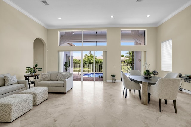 dining room with arched walkways, a towering ceiling, visible vents, and crown molding