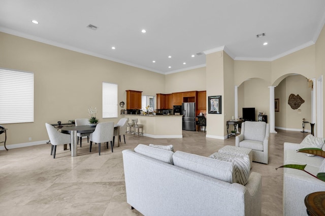 living area featuring arched walkways, baseboards, visible vents, and ornate columns