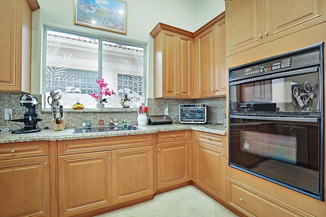 kitchen with black appliances, light stone counters, backsplash, and a toaster