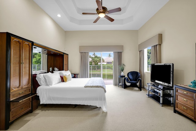 bedroom featuring access to outside, a high ceiling, a raised ceiling, and light colored carpet