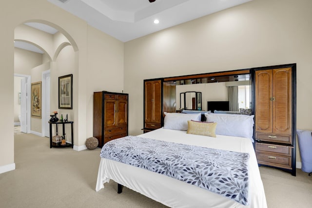 bedroom with arched walkways, recessed lighting, a towering ceiling, light carpet, and baseboards