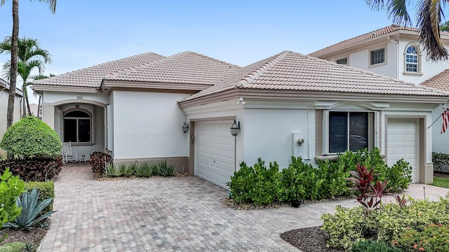 view of front of property with a garage, a tile roof, decorative driveway, and stucco siding