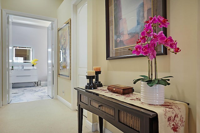 hallway with marble finish floor, a sink, and baseboards