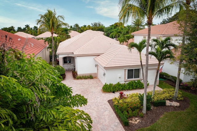 mediterranean / spanish home featuring a tiled roof, decorative driveway, and stucco siding