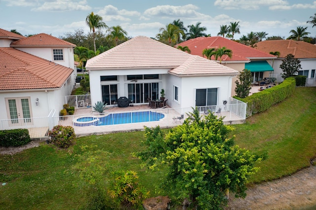 rear view of house featuring a lawn, a patio, a tiled roof, fence, and stucco siding