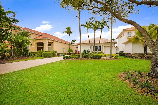 view of front of house with driveway, a front yard, a tiled roof, and stucco siding