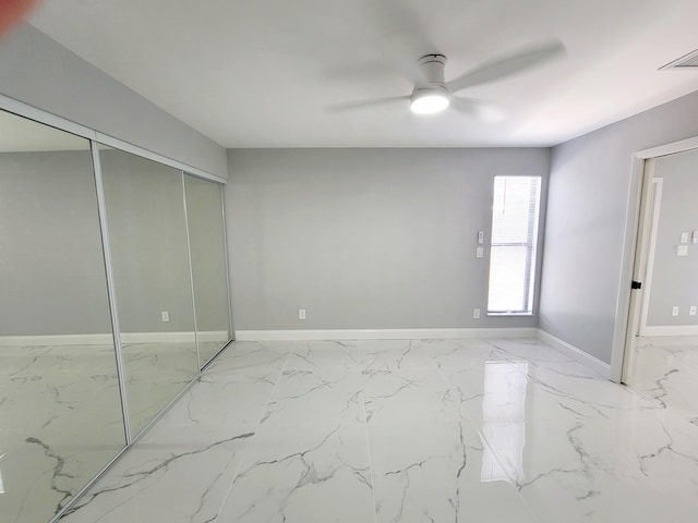 unfurnished bedroom with visible vents, baseboards, a ceiling fan, marble finish floor, and a closet