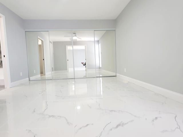 unfurnished room with marble finish floor and baseboards