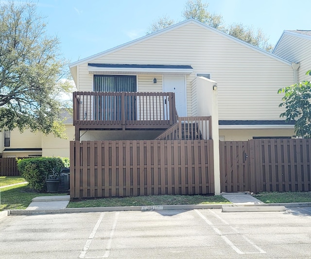 view of front of property with uncovered parking, fence, and a balcony