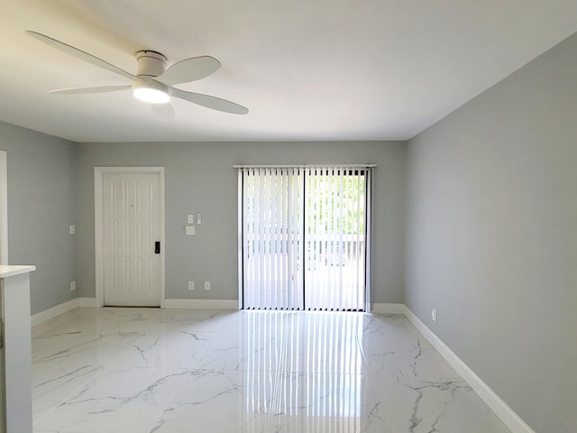 empty room featuring marble finish floor, baseboards, and a ceiling fan