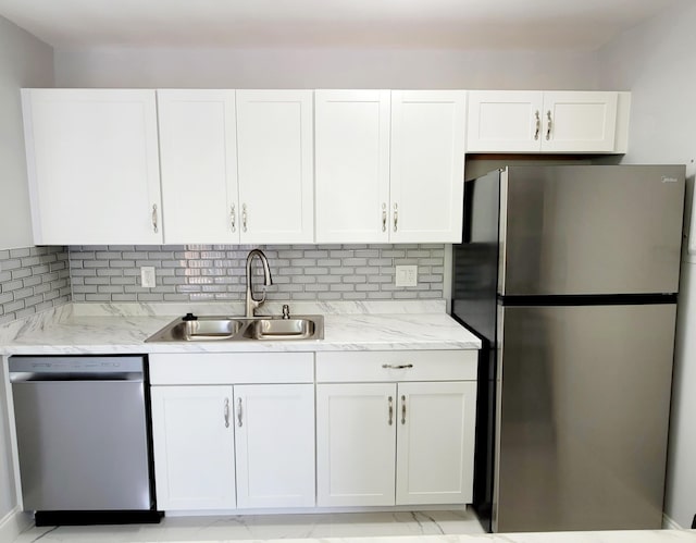 kitchen with appliances with stainless steel finishes, white cabinets, a sink, and decorative backsplash