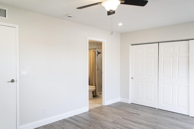 unfurnished bedroom with a closet, a ceiling fan, connected bathroom, wood finished floors, and baseboards