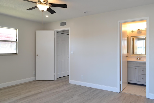 unfurnished bedroom with light wood finished floors, baseboards, visible vents, and a sink