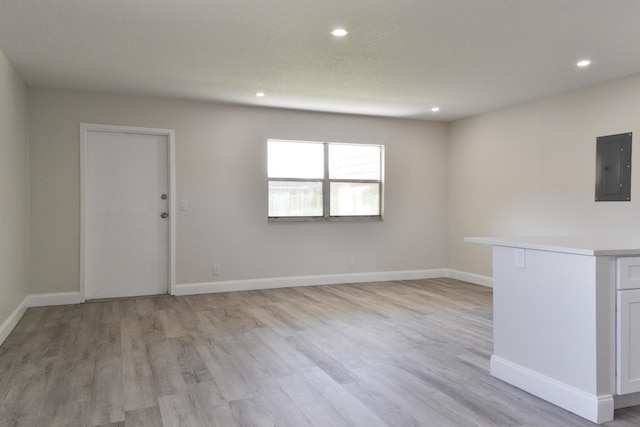 unfurnished room featuring light wood-type flooring, electric panel, baseboards, and recessed lighting