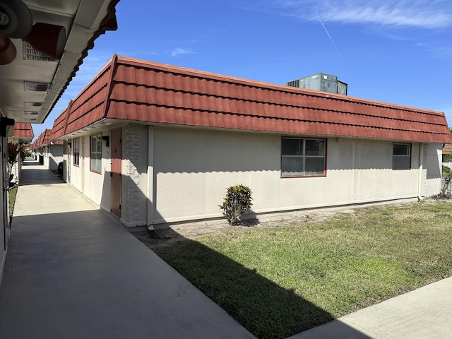 view of side of home with a tile roof and stucco siding