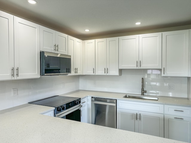 kitchen featuring tasteful backsplash, appliances with stainless steel finishes, white cabinets, and a sink