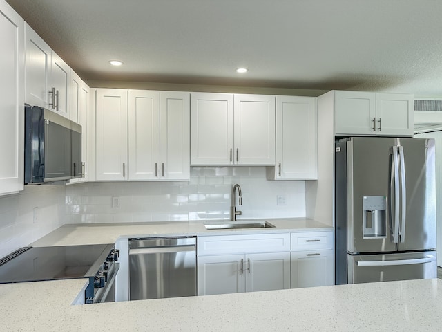 kitchen featuring stainless steel appliances, tasteful backsplash, a sink, and white cabinetry