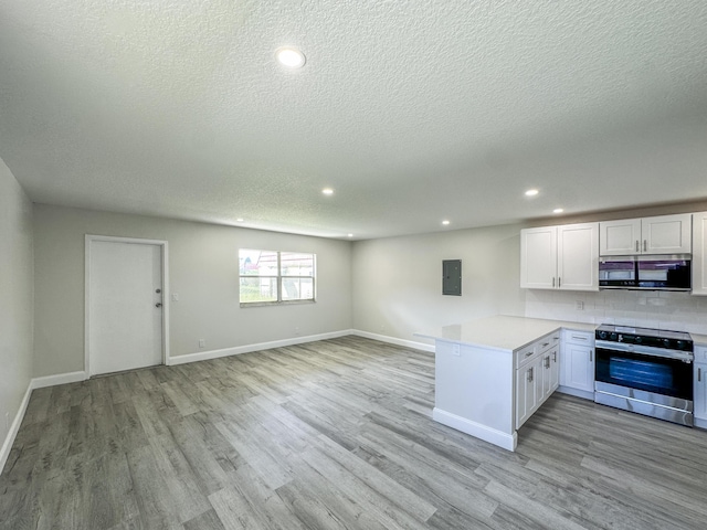 kitchen with light countertops, light wood-style floors, stainless steel range with electric cooktop, electric panel, and a peninsula