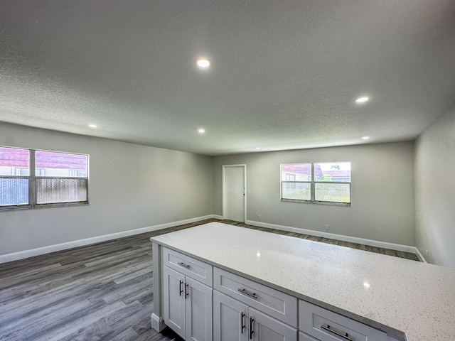 kitchen featuring a textured ceiling, baseboards, dark wood-style flooring, and recessed lighting