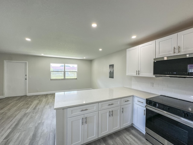 kitchen featuring recessed lighting, appliances with stainless steel finishes, white cabinetry, light wood-type flooring, and a peninsula