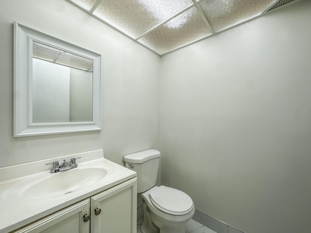 half bathroom with visible vents, toilet, marble finish floor, vanity, and a paneled ceiling