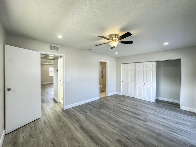 unfurnished bedroom featuring a closet, visible vents, a textured ceiling, wood finished floors, and baseboards