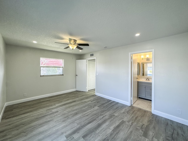 unfurnished bedroom featuring visible vents, baseboards, a sink, and wood finished floors