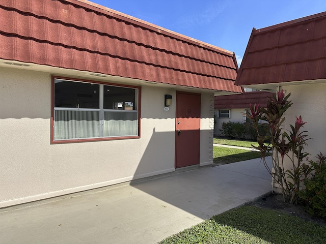 doorway to property with a tiled roof and stucco siding