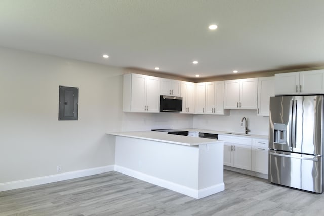 kitchen featuring stainless steel appliances, light countertops, a sink, electric panel, and a peninsula