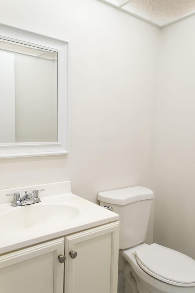 bathroom featuring a textured ceiling, vanity, and toilet