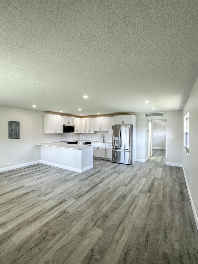 kitchen with electric panel, visible vents, white cabinets, stainless steel appliances, and light wood-style floors