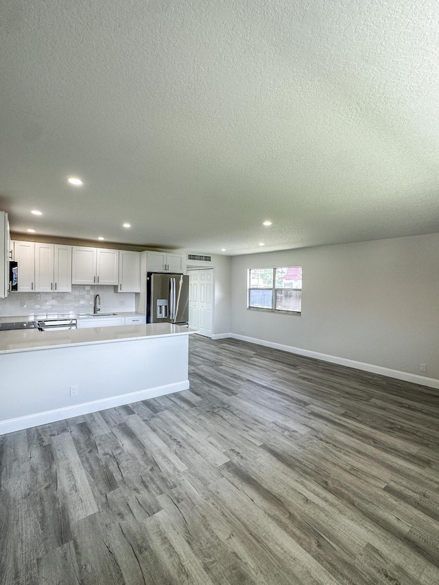 unfurnished living room featuring dark wood finished floors, a sink, and baseboards