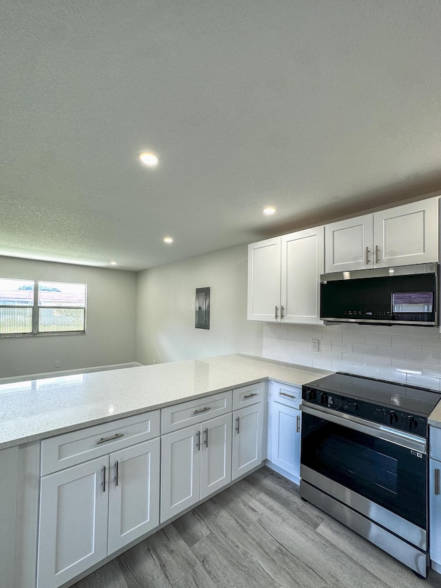 kitchen featuring light wood finished floors, light stone countertops, stainless steel electric stove, white cabinetry, and recessed lighting