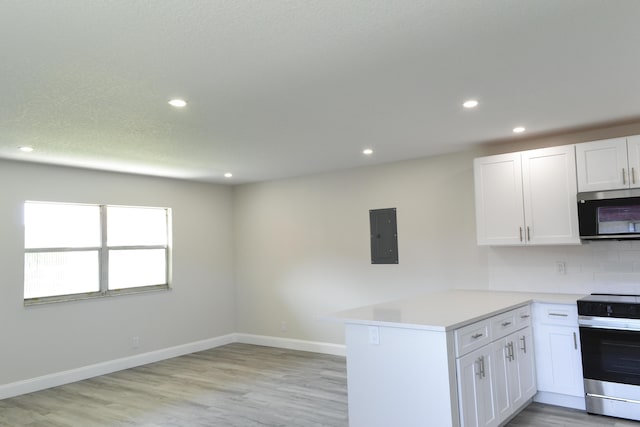 kitchen featuring stainless steel appliances, a peninsula, white cabinets, light wood-type flooring, and electric panel