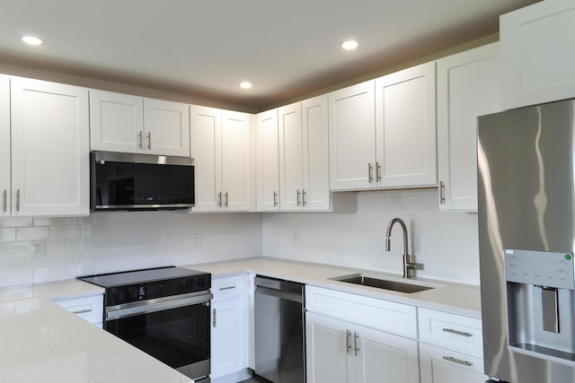 kitchen featuring recessed lighting, a sink, white cabinetry, appliances with stainless steel finishes, and decorative backsplash