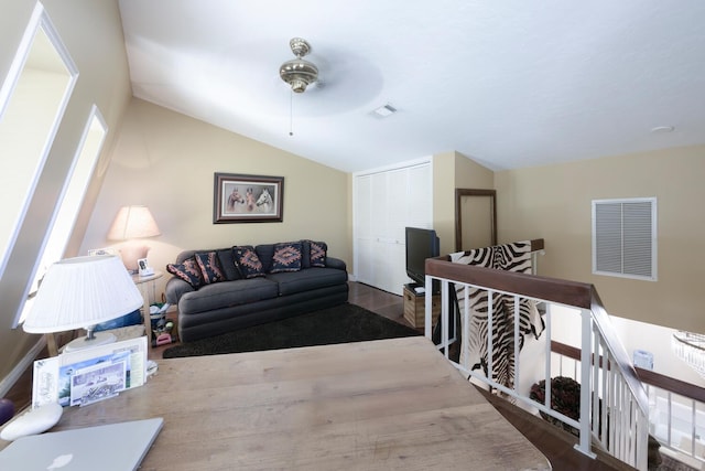 living area with a ceiling fan, visible vents, vaulted ceiling, and wood finished floors