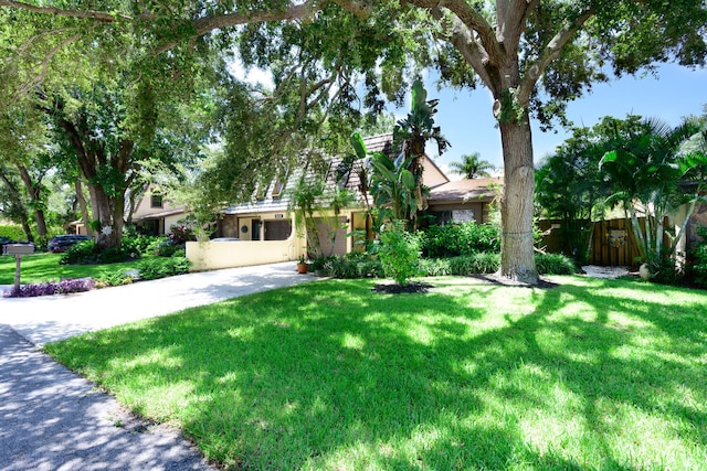 obstructed view of property featuring stucco siding, fence, and a front yard