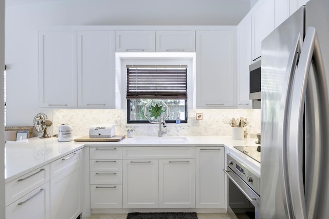 kitchen featuring white cabinets, backsplash, stainless steel appliances, and a sink