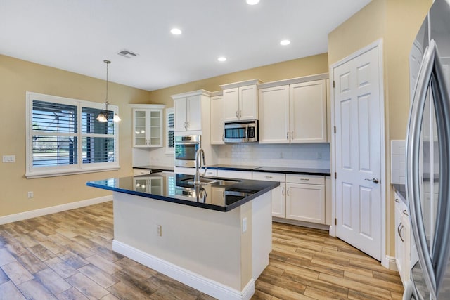 kitchen with hanging light fixtures, appliances with stainless steel finishes, dark countertops, and white cabinetry