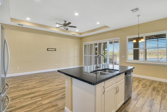 kitchen with a sink, visible vents, white cabinets, dark countertops, and a raised ceiling