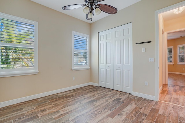 unfurnished bedroom featuring light wood-type flooring, a ceiling fan, baseboards, and a closet