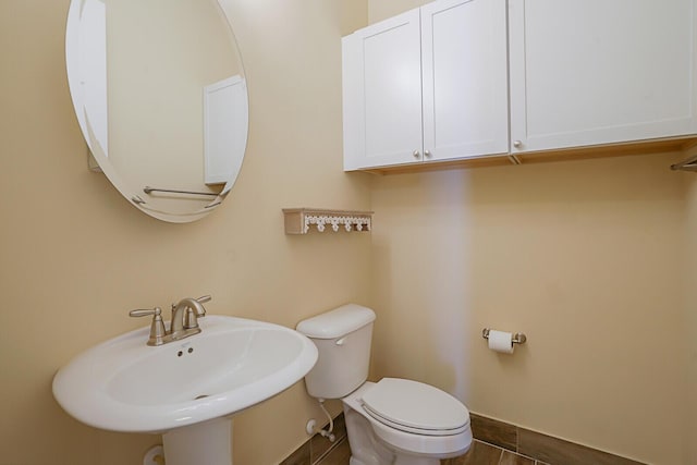 bathroom with toilet, baseboards, and a sink