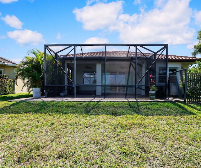 rear view of property with a yard, a patio, a lanai, and a tiled roof