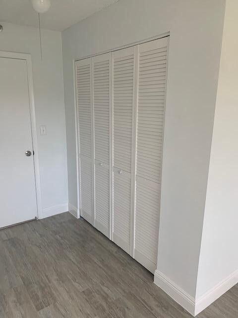 unfurnished bedroom with dark wood-style floors, a closet, and baseboards