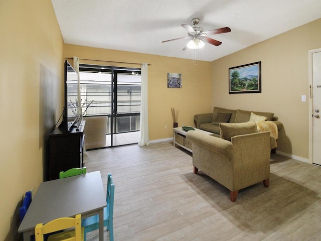 living room with light wood-style floors, baseboards, and a ceiling fan