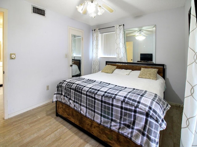 bedroom with visible vents, baseboards, and wood finished floors